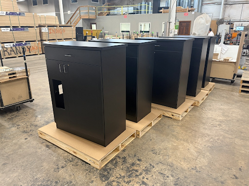 A row of black modular cabinets sits on wood pallets in a warehouse.